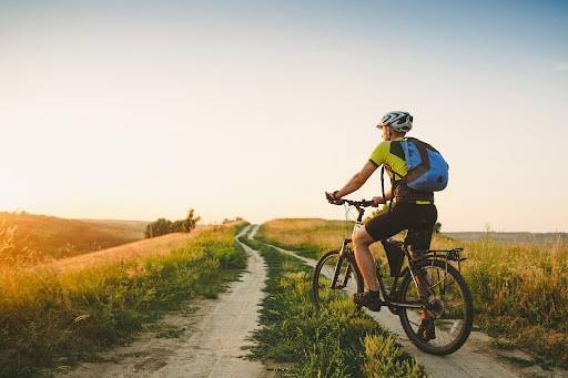 Happy smiling woman rides a bicycle on the country road