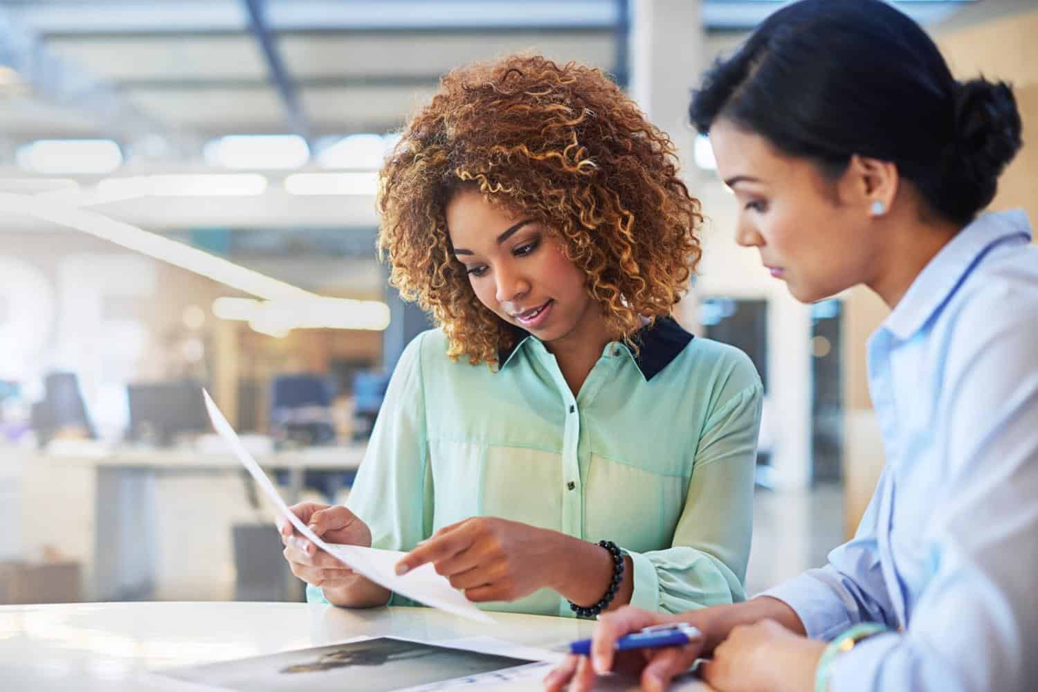 Two people depicting the scene of a leader reviewing feedback with their executive coach