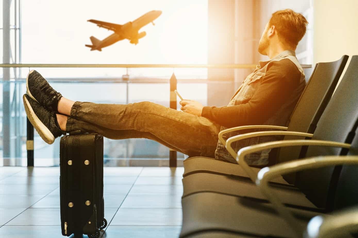 Man sitting at the airport watching a plane take off
