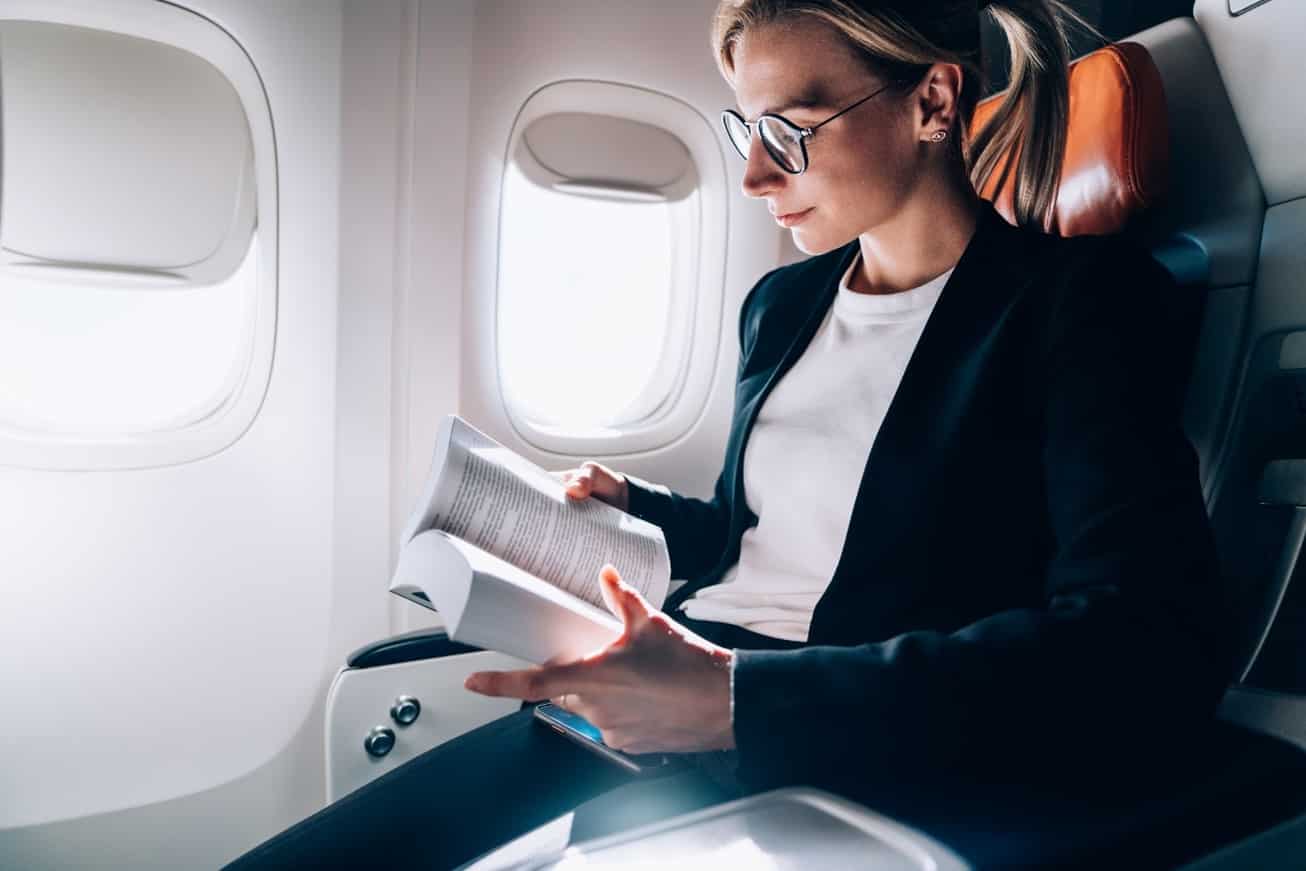 Businesswoman reading personal development book on plane