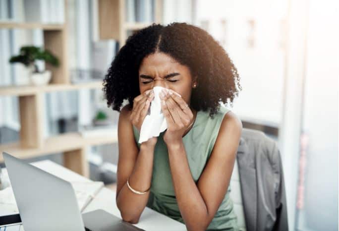 Businesswoman blowing her nose at desk