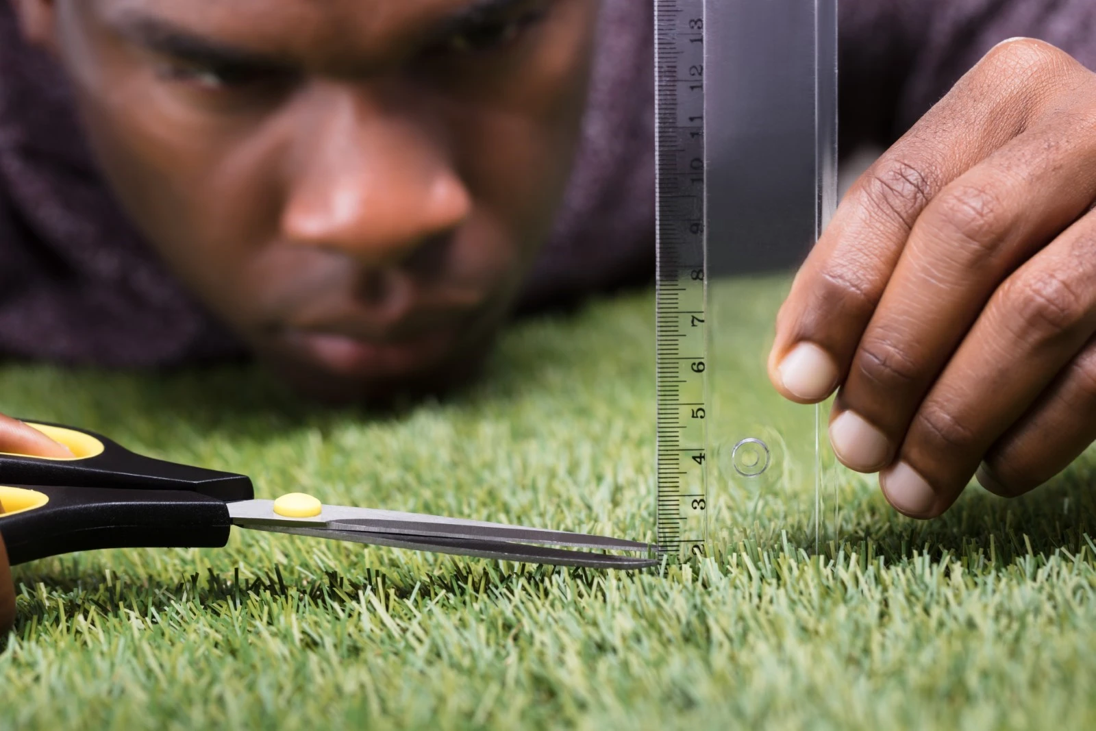 Perfectionist man cutting grass with a ruler